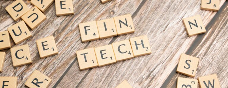 Fintech spelled out with wooden letter tiles on a rustic wooden background.